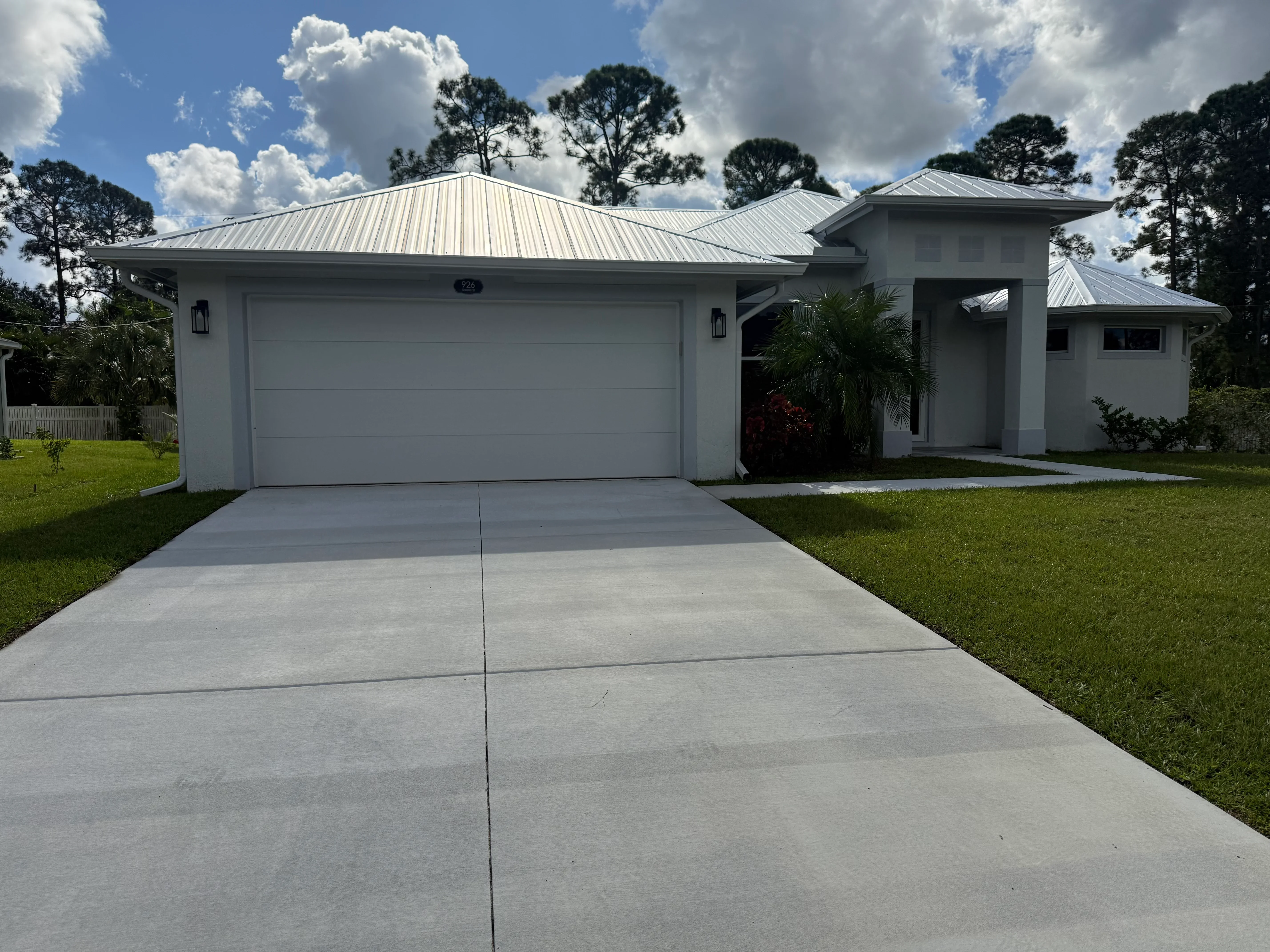 White paneled garage door on modern white home with metal roof in Palm Bay