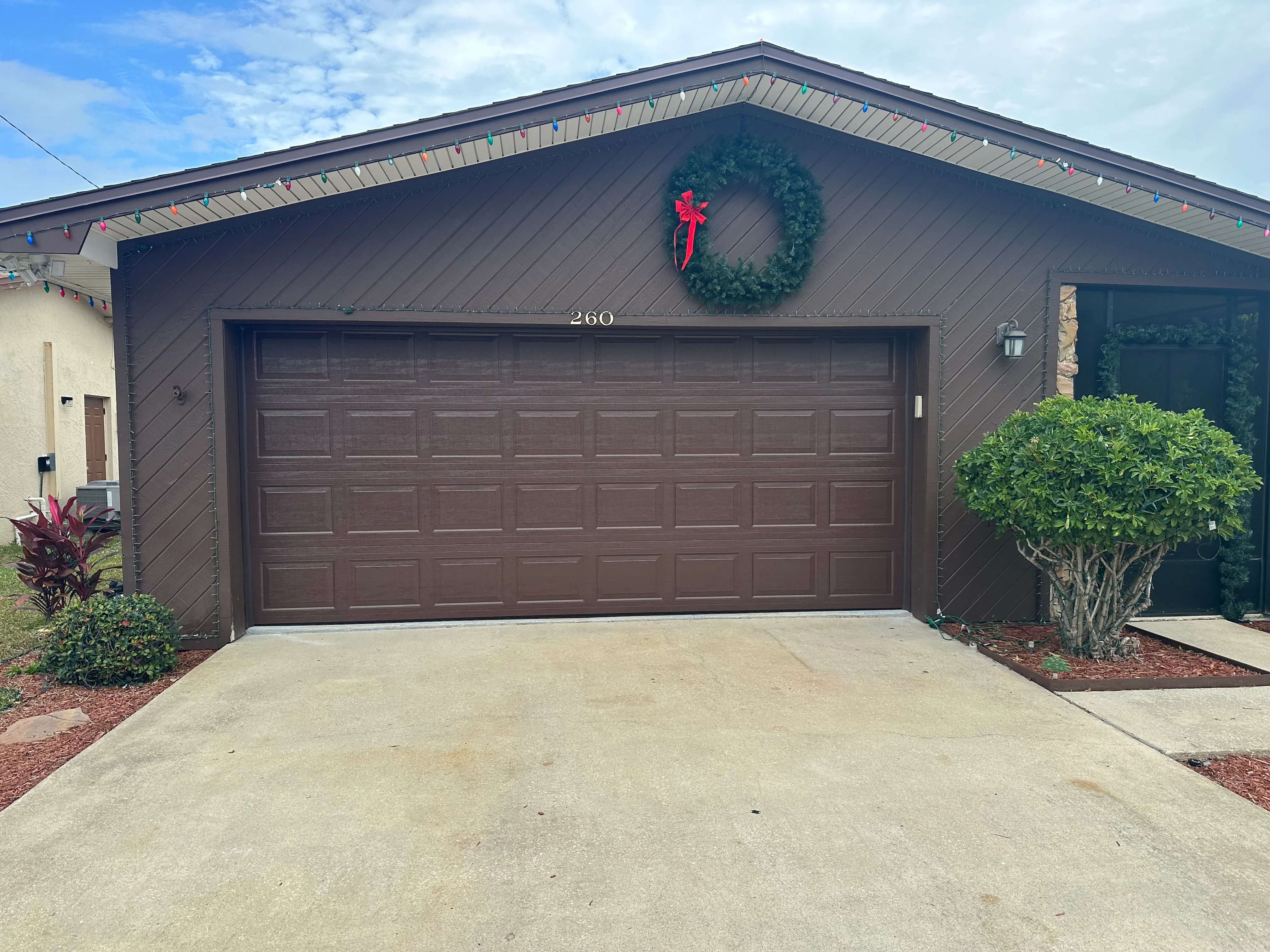 Dark brown garage door on modern home with vertical siding in Palm Bay