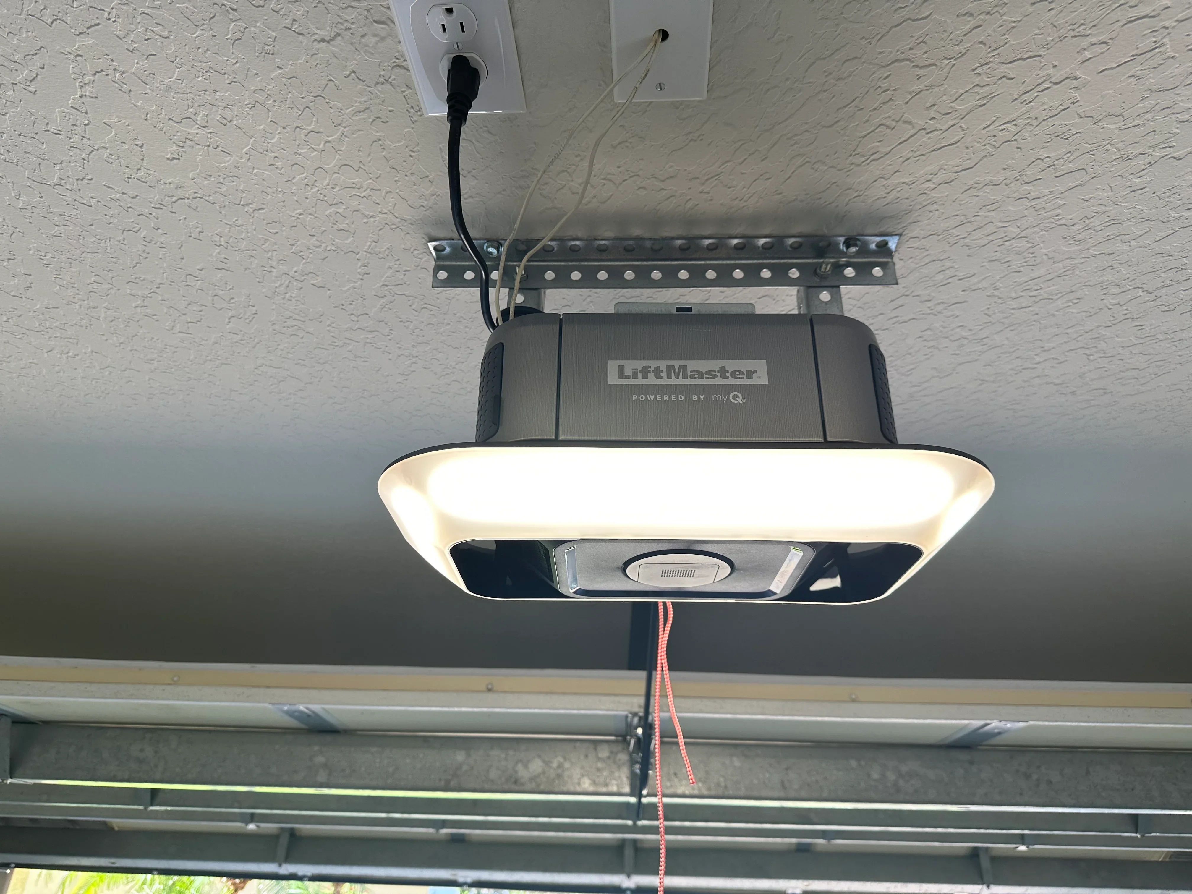 LiftMaster smart garage door opener installed on textured garage ceiling with mounting hardware