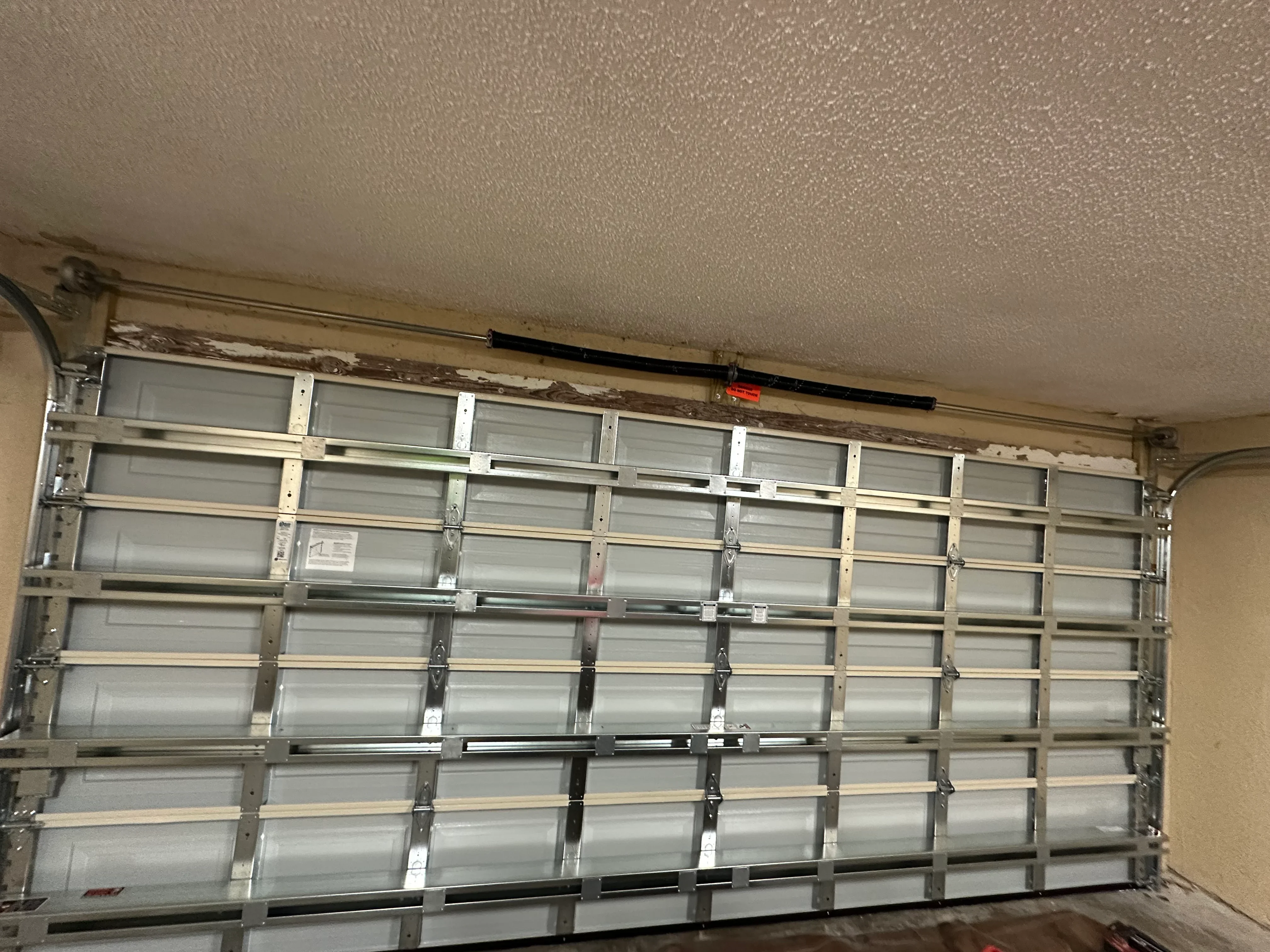 Newly installed multi-panel aluminum and frosted glass garage door with horizontal sections and metal framing