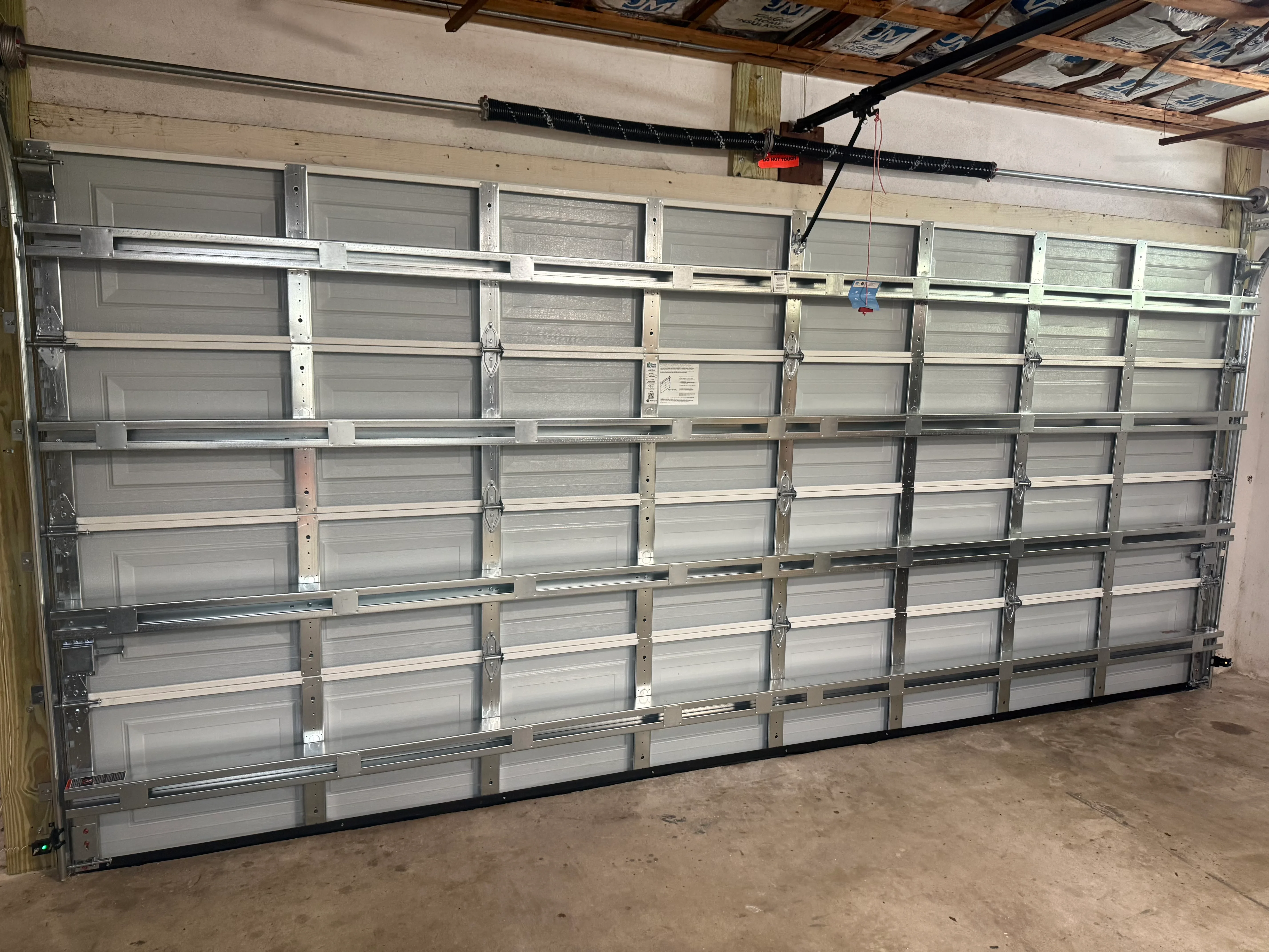Newly installed gray aluminum garage door with frosted glass panels in garage interior